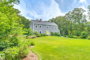 une maison grise avec une cour avec une grande pelouse dans l'établissement Pool, Sunroom and Gardens Luxe Sandy Hook Home!, 