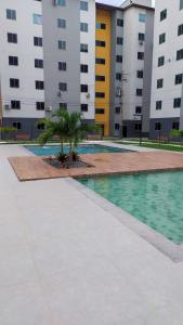 a swimming pool with palm trees in front of buildings at Apto c TV Streaming Ar Wifi e Piscina in Ananindeua