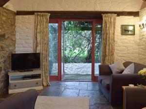 ein Wohnzimmer mit Sofa und Fernseher in der Unterkunft Beats Cottage in Llangwm