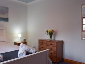 ein Schlafzimmer mit einem Bett und einer Blumenvase auf einer Kommode in der Unterkunft Beats Cottage in Llangwm + 4 Fotos