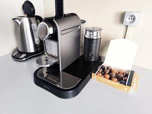 a coffee maker on a counter next to a box of donuts at LeRelaisdOdile-Idéal Pro & Famille-Proche Métro-Fort de Mons in Mons-en-Baroeul