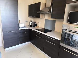 a kitchen with black cabinets and a microwave at LeRelaisdOdile-Idéal Pro & Famille-Proche Métro-Fort de Mons in Mons-en-Baroeul +22 photos