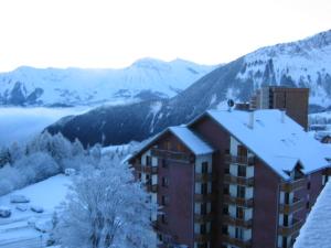 a building covered in snow with mountains in the background at Appartement T3 - 3 étoiles - 6 pers - Au pied des pistes in Villarembert