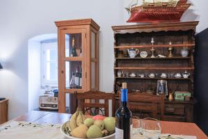 a bowl of fruit on a table with a bottle of wine at 'Perithyron', Konstantina's House, Old Perithia - An Authentic stone Retreat in Corfu's most Historic Village in Ypsilás