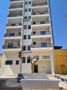 een hoog wit gebouw met een boom ervoor bij MarMeg Guesthouse in Tirana