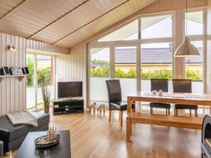 Huus Naturstrand am Diek في Wesselburen: غرفة معيشة مع طاولة وكراسي ونوافذ