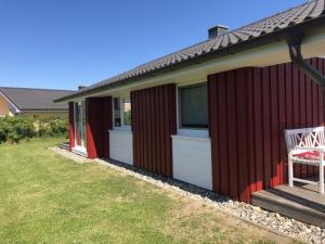 Huus Naturstrand am Diek في Wesselburen: منزل احمر مع ساحه مع كرسي +9 صور