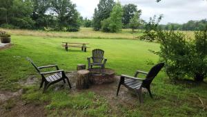 three chairs and a fire pit in a yard with a bench at Solitude Junction in Opdyke +6 photos