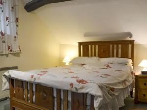 a bedroom with a large bed with a wooden headboard at Ivy Cottage in Elton