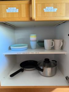 a shelf with bowls and plates and a pot at Comfort rooms near Zürich Airport in Embrach
