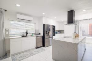 a kitchen with white cabinets and a stainless steel refrigerator at Backyard Oasis Private Villa Pool Hot Tub in El Cajon
