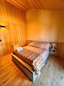 ein Schlafzimmer mit einem Bett in einem Zimmer mit Holzwänden in der Unterkunft alquiler temporario en villa la angostura in Villa La Angostura
