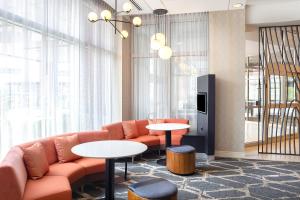 a living room with a couch and tables and windows at Courtyard by Marriott Buffalo Downtown/Canalside in Buffalo