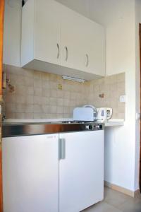 a kitchen with white cabinets and a white refrigerator at Villa Anna Maria in Agia Paraskevi