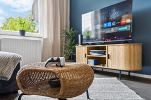 a wicker chair in a living room with a television at Business Apartment Alte Post in Unterlüß +1 photo