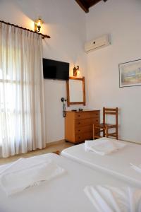 a bedroom with two beds and a dresser and a mirror at Villa Anna Maria in Agia Paraskevi