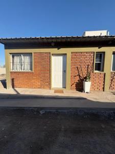 a brick house with a white door on a street at Alojamiento cuyum in Rivadavia