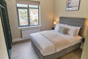 a bedroom with a large bed with a window at Riverside Dingle - Luxury Apt 4 in Dingle
