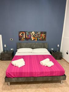a bedroom with a pink bed with two towels at Dalle ziette! in Civitavecchia