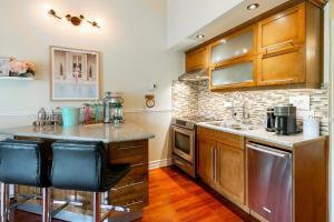 a kitchen with wooden cabinets and a counter with bar stools at Charming Tremblant 1 Bedroom -Pool Hot Tub in Mont-Tremblant