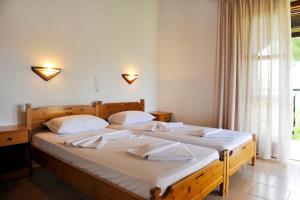 a bedroom with two beds with white sheets and a window at Villa Anna Maria in Agia Paraskevi