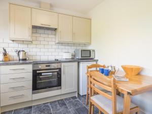 a kitchen with white cabinets and a wooden table at 3 Bed in Braithwaite SZ045 in Braithwaite