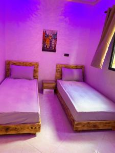 two beds in a room with purple lighting at Appartement Calme (1) in Fès