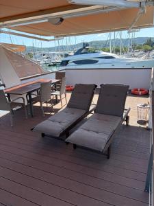 ein Deck mit zwei Liegestühlen und einem Tisch und einem Boot in der Unterkunft Marina Luxury Houseboat Lace in Portorož