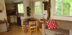 a kitchen and living room with a couch and a table at Stacaravan 4 persoons - Camping Le Soustran in Neuvic