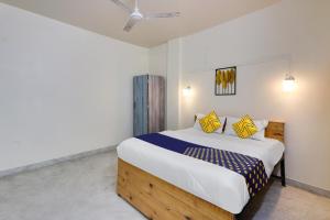 a bedroom with a large bed with yellow and blue pillows at SPOT ON Hotel Blue Moon in Nagpur