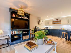 Una cocina con gabinetes azules y un televisor y una mesa. en 1 Bed in cotswolds 90128, en Cirencester 13 fotos más
