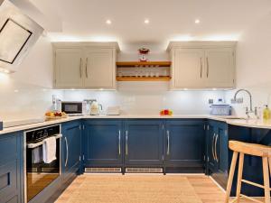 una cocina con armarios azules y electrodomésticos blancos en 1 Bed in cotswolds 90128, en Cirencester