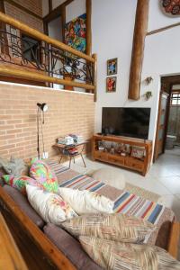 Una sala de estar con un sofá y un televisor. en Mirantes Paraibuna - Casa Vermelha, en Paraibuna