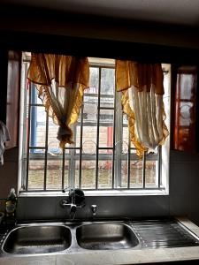 a kitchen window with curtains over a sink at Axis Guest House in Syokimau +45 photos