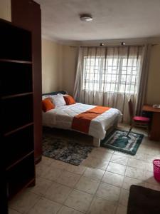 a bedroom with a bed in front of a window at Axis Guest House in Syokimau