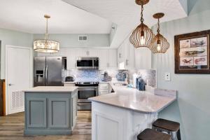 une cuisine avec des placards blancs et un îlot bleu dans l'établissement Summer House 1402A, à Romar Beach