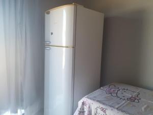 a white refrigerator in a room with a table at Hospedagem 24 de Junho in Barra do Garças
