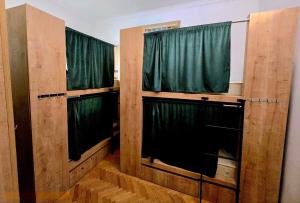 a room with two windows with green curtains at Colors Hostel in Tbilisi City