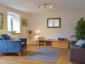 Una sala de estar con dos sillas azules y una mesa. en West Barn - Uk31850, en Trecwn