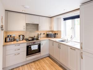 a kitchen with white cabinets and a sink and a window at 2 Bed in Westward Ho 45753 in Northam +4 photos