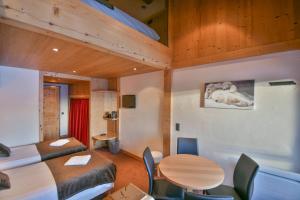 a room with a bed and a table and chairs at Hotel les Flocons in Le Grand-Bornand