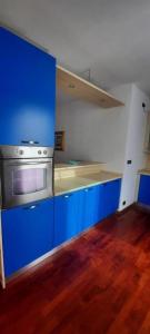 a kitchen with blue cabinets and a stainless steel stove at PM 23 Via Rogge Guest House in Rosà +3 photos