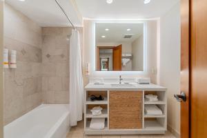 a bathroom with a sink and a tub and a mirror at Humphreys Half Moon Inn in San Diego