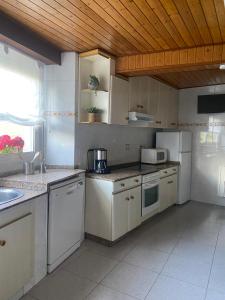 a kitchen with white appliances and a wooden ceiling at VUT Rural 2 in Arzúa +17 photos