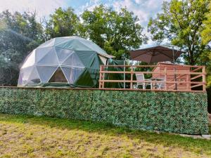 a tent on a wall with a table and an umbrella at Glamping Dôme Benzène in Fonmourenne