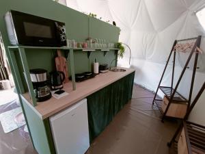 a kitchen with green cabinets and a microwave at Glamping Dôme Benzène in Fonmourenne