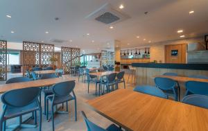 a restaurant with wooden tables and blue chairs at Soft Inn Alagoinhas in Alagoinhas