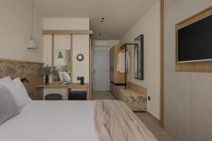 a bedroom with a bed and a desk and a tv at Lumora Suites in Kavos