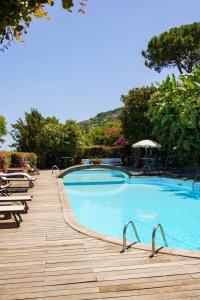 a swimming pool with chairs and a wooden deck at Villa Massimo Cartaromana with wide pool and view on the Castle in Ischia
