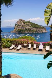 a pool with chairs and a castle in the background at Villa Massimo Cartaromana with wide pool and view on the Castle in Ischia